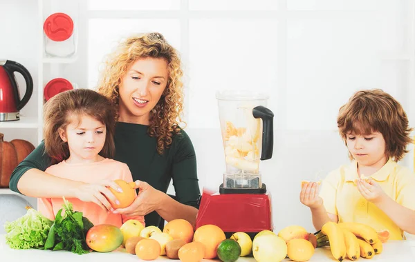 Mãe com crianças fazendo smoothie em uma cozinha branca. Família mãe e filho filha e filho misturado smoothie com ingredientes de frutas saudáveis. Smoothie desintoxicação e alimentos saudáveis. — Fotografia de Stock