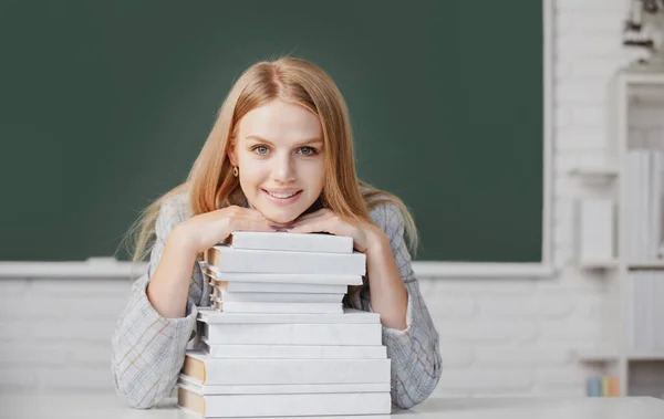 Porträtt av kvinnliga universitetsstuderande lektion i skolan eller universitetet. Närbild porträtt av glad attraktiv ung kvinna student med böcker om svarta tavlan i klassrummet. — Stockfoto