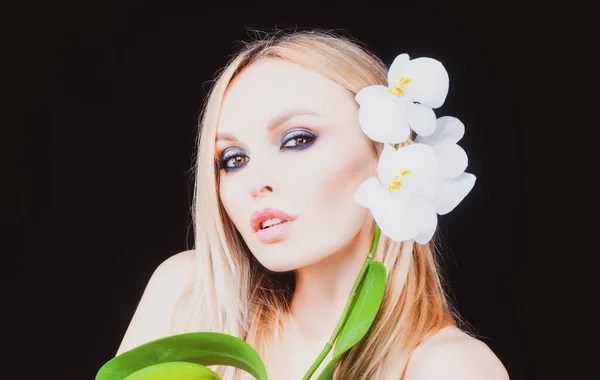 Salute di bellezza. Donna con fiore di orchidea. Prodotti cosmetici. — Foto Stock