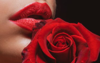 Dudakları rujla yakın plan. Kırmızı güllü bir kadın, makro, siyah arka planda. Güllü güzel kadın dudakları.