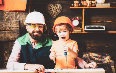 Marangozluk, ahşap işçiliği ve insan konsepti. Tornavidalı baba ve oğlu atölyedeki tahtaya vidalıyorlar..