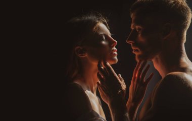 Karanlık arka planda gece lambalarıyla poz veren güzel bir çift. Flört ederken kucaklaşan seksi bir çiftin duygusal portresi. Siyaha aşık genç bir çift. Bu sevimli çift birlikte vakit geçiriyor..