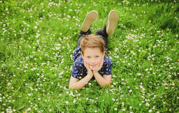 Voorjaarsjongen. Gelukkige jeugd. Lachend kind liggend op gras. Droomconcept. — Stockfoto