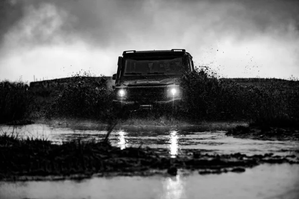 Rad aus nächster Nähe in einer Landschaft mit schlammiger Straße. Wasserspritzer im Offroad-Rennen. Geländewagen kommt aus Schlammloch. — Stockfoto