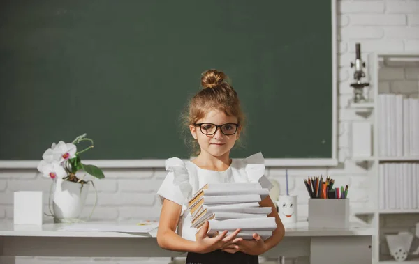 Porträt eines süßen, lieblichen Mädchens in Schuluniform im Klassenzimmer. Nerd-Schulmädchen mit Brille und Büchern an der Tafel. — Stockfoto