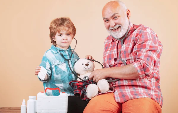 Parenting. Old man with scarf holding a blister of pills in his hands. Patient recovery is going well. Little doctor giving grandfather medicament.