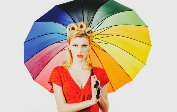 Pinup chica con paraguas de arco iris en el tiempo de lluvia. Lluvioso estado de ánimo otoñal, pin up mujer vestido rojo aislado blanco. —  Fotos de Stock