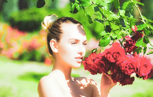Słodka dziewczyna z kwiatem stojącym na polu róż, na świeżym powietrzu. Sezon wiosenny. — Zdjęcie stockowe