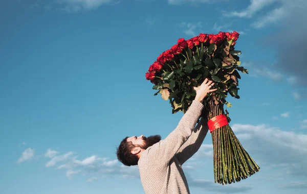 头戴红玫瑰花束的男人。 情人节。 带着爱的礼物 背景天空中英俊的男人。 情人节送的礼物. — 图库照片