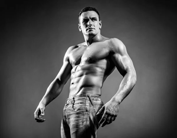 Porträtt snygg sexig muskulös man, idrottsman med perfekt kropp över mörk bakgrund. Sexig muskel stark ansikte kille i jeans på grå studio isolerad. — Stockfoto