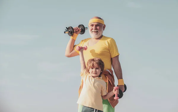 Vida familiar saludable. El abuelo y el nieto practican ejercicios de mancuernas al aire libre. Concepto de motivación y ejemplo deportivo . — Foto de Stock