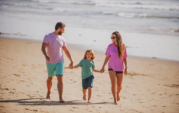 父亲、母亲和孩子手牵手在海滩上散步. — 图库照片