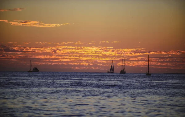 Barco en el mar al atardecer. Veleros con velas. Océano yate a lo largo del agua. — Foto de Stock