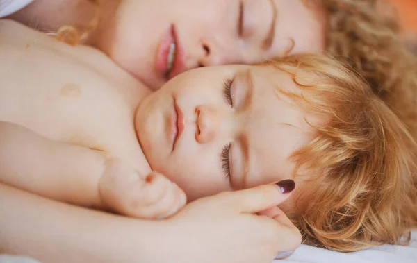 Mutter und Baby schlafen im Bett. Familienmorgen im Schlafzimmer. Gesichter aus nächster Nähe. — Stockfoto