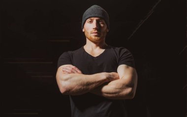 Kollarını kavuşturmuş genç ve seksi bir adamın portresi. Siyah stüdyoda erkek model..