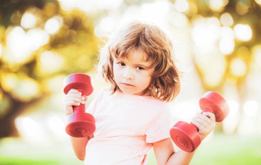 Çocuklar dışarıda halterlerle egzersiz yapıyor. Çocuk için spor.