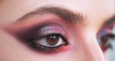 Mor dumanlı göz makyajı. Yakın çekim fotoğrafı. Profesyonel dumanlı gözler, özel durumlar için güzel bir kıza makyaj yapar. Göz makyajındaki parlak pigmentler. Lüks göz makyajı konsepti.