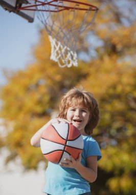 Sevimli çocuk basketbol oynuyor, gülüyor ve eğleniyor..