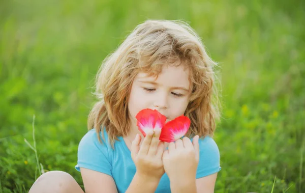 Close up retrato de um pequeno menino loiro cheirando flores. Crianças curtindo verão. — Fotografia de Stock