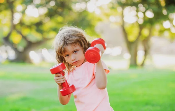 Kinderen sporten. Jongen aan het trainen in het park. Actieve, gezonde levensstijl. Sport kind met sterke biceps spieren trainen halter. — Stockfoto