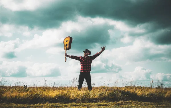 Uomo escursionista eccitato con chitarra guardando bella vista. Uomo hipster escursionista nel campo autunnale. — Foto Stock