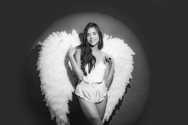 Angel wings. Angelic beautiful woman. Wonderful blonde angel girl with white wings. Beautiful fairy flying girl in white dress