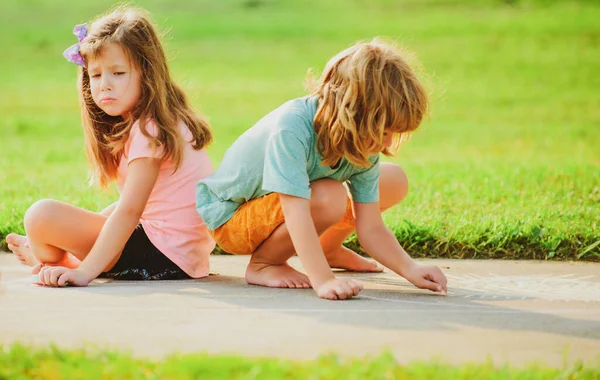 Детские отношения и адаптация. Двое детей играют на свежем воздухе. Мальчик и грустная девочка в парке. — стоковое фото
