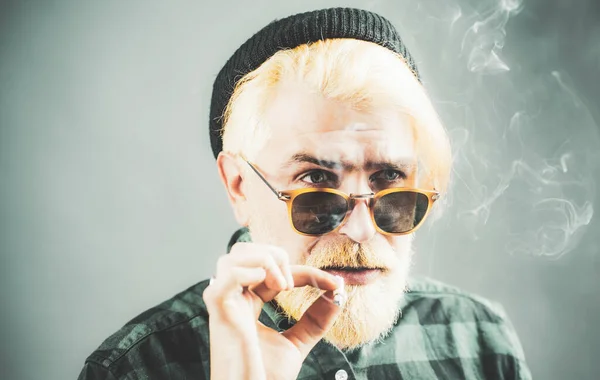 Homem bonito com grande sorriso vestindo óculos de moda contra fundo escuro com espaço de cópia . — Fotografia de Stock