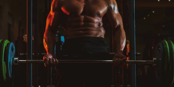 Hombre musculoso haciendo bíceps levantando la barra. Hombre muscular haciendo ejercicio en el gimnasio haciendo ejercicios, fuertes abdominales masculinos desnudos del torso. —  Fotos de Stock