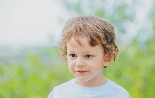 Retrato de uma criança feliz sorrindo e se divertindo. Rapazinho feliz. Retrato emocional de um menino em um passeio em um parque da cidade. Criança feliz no verão na natureza. Criança brincando ao ar livre. — Fotografia de Stock