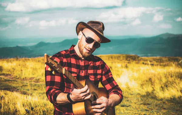 Man with guitar on nature. Hipster plays guitar on Camping holiday. — Stock Photo, Image