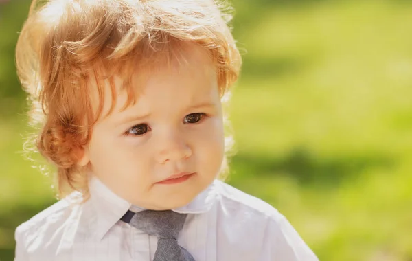 Lustigt barnansikte. Utomhus porträtt av söt liten pojke i kostym och slips. Liten affärsman. — Stockfoto