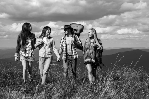 幸せな友人が自然の上を歩く。男性と若い女の子のグループは、夏の日に自由を感じています。休暇を楽しむ人々. — ストック写真