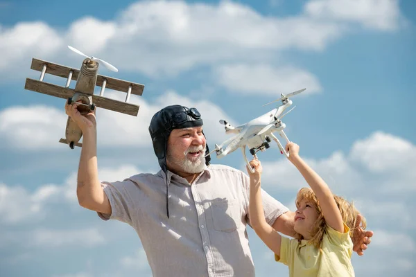 Grand-père et fils avec avion et quad copter drone sur ciel bleu. Hommes génération grand-père et petit-enfant. Aîné parent âgé avec enfant. — Photo