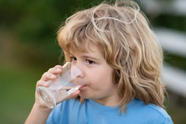 Bambino acqua potabile all'aperto nel parco. Ragazzo che beve. Close up ritratto del ragazzo bere acqua dal vetro in giardino. — Foto Stock