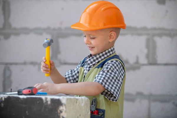 Kleine jongen in oranje beschermhelm met instrumenten voor renovatie. Reparatie thuis. — Stockfoto