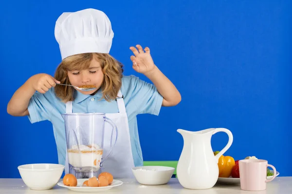 Готовить детей. Мальчик-повар делает свежие овощи для здорового питания. Портрет маленького ребенка в виде повара изолирован на сером фоне. Детский повар. Процесс приготовления. — стоковое фото