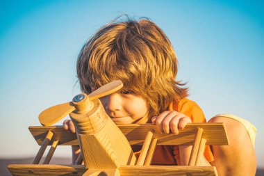 Çocuk rüya görüyor ve parkta oyuncak bir uçakla oynuyor. Seyahat hayalleri. Geliştirme, büyüme, hayaller ve planlar. Hayal gücü ve rüya kavramı. Çocuklarla yaz tatili.