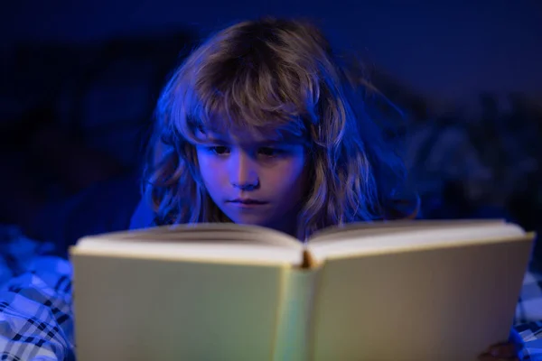 Lycklig barndom, drömmande barn. Barn läser en magisk bok i sängen. Grabben läste böcker hemma.. — Stockfoto