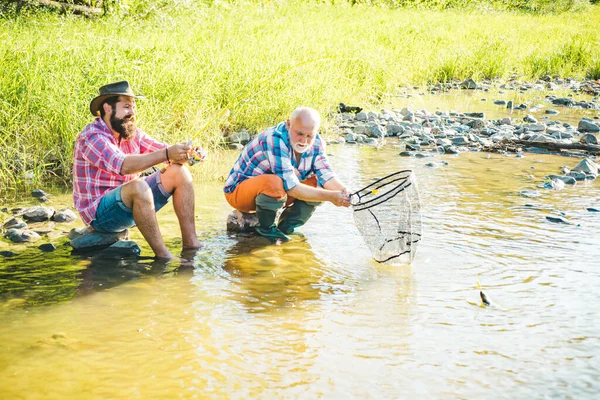Пожилой мужчина с другом по рыбалке. Летние каникулы. Счастливые веселые люди. Бородатые люди ловят рыбу. Рыбак с удочкой. Деятельность и хобби. — стоковое фото