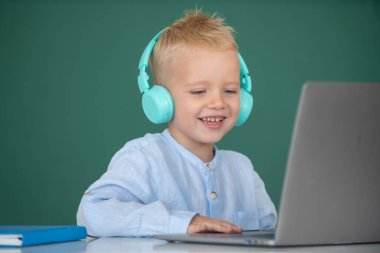 Dizüstü bilgisayar kullanan şirin bir çocuk, online e-öğrenme yoluyla okuyan bir çocuk. Küçük komik sistem yöneticisi. Okuldaki ilk günüm..
