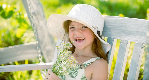 Yazın çiçeklerin arka planındaki sevimli sarışın kız çocuğu. Bahçede çalışan güzel bir çocuk, çiçeklerle ilgilenen bir çocuk, sıcak ve güneşli bir günün tadını çıkarıyor.. — Stok fotoğraf