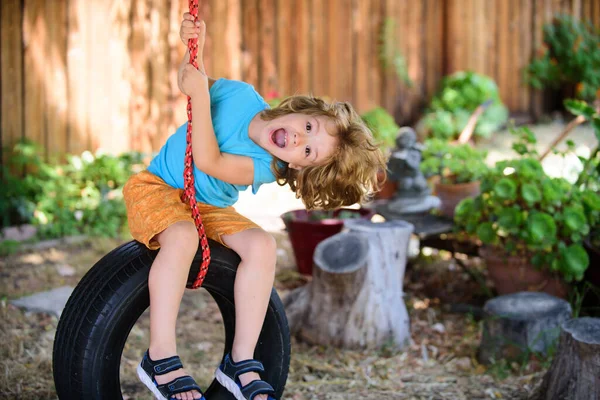 Criança brincando no parque infantil. Criança activa no parque infantil. As crianças brincam na escola ou no jardim de infância. Engraçado garoto menino se divertindo com corrente swing no playground ao ar livre. — Fotografia de Stock