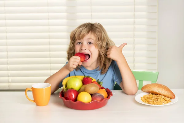 Child with strawberry, summer fruits. Kid preteen boy in the kitchen at the table eating vegetable and fruits during the dinner lunch. Healthy food, vegetable dish for children. — Stock Photo, Image