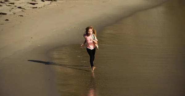 Niño corriendo a lo largo del océano. El chico corre en la playa de arena. Carrera y deporte saludable para los niños. — Foto de Stock