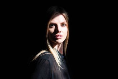 Siyah stüdyoda gölgeli, güzel yüzlü seksi bir kadın. Şehvetli kız..