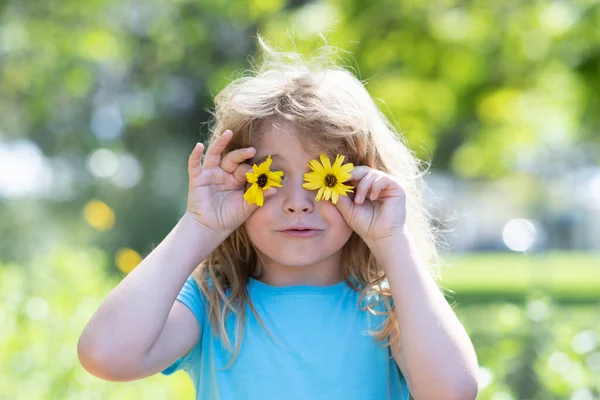 Portret wiosennych dzieci, śmieszna twarz. Mały chłopiec wącha kwiaty na zielonym podwórku. Urocze dziecko na letniej łące i pachnące kwiatami. — Zdjęcie stockowe