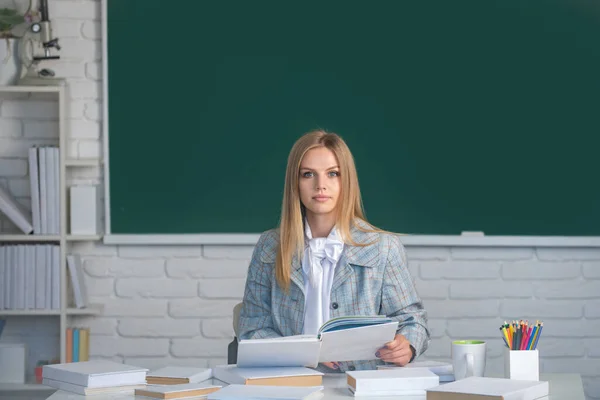 Student przygotowuje egzamin i lekcje w klasie szkolnej. Poważny student czytania książki na tle tablicy z miejsca do kopiowania. — Zdjęcie stockowe
