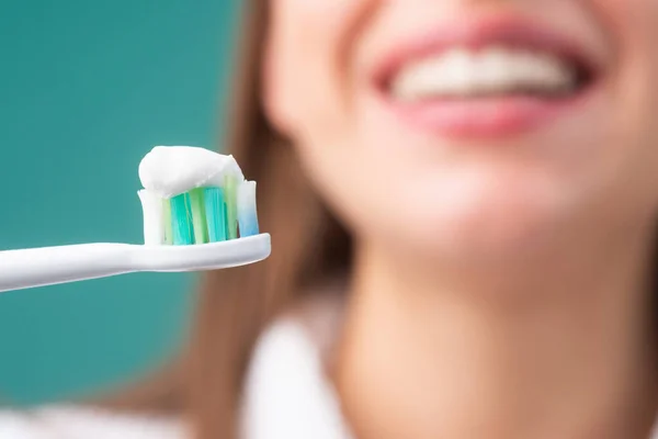 Tandenborstel met tandpasta. Dichtbij een vrolijke jonge vrouw die tanden poetst. Close-up mond met tandenborstel. — Stockfoto