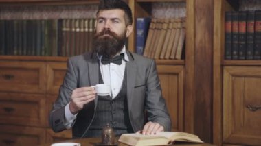 Düşünen adam. Klasik takım elbiseli adam kütüphanede kitap okuyor. Klasik takım elbiseli iş adamı kitap okudu. Eski moda iş adamları. Kitap okuyan, kitaplıkta çay içen bir adam. İngilizce klasik stil